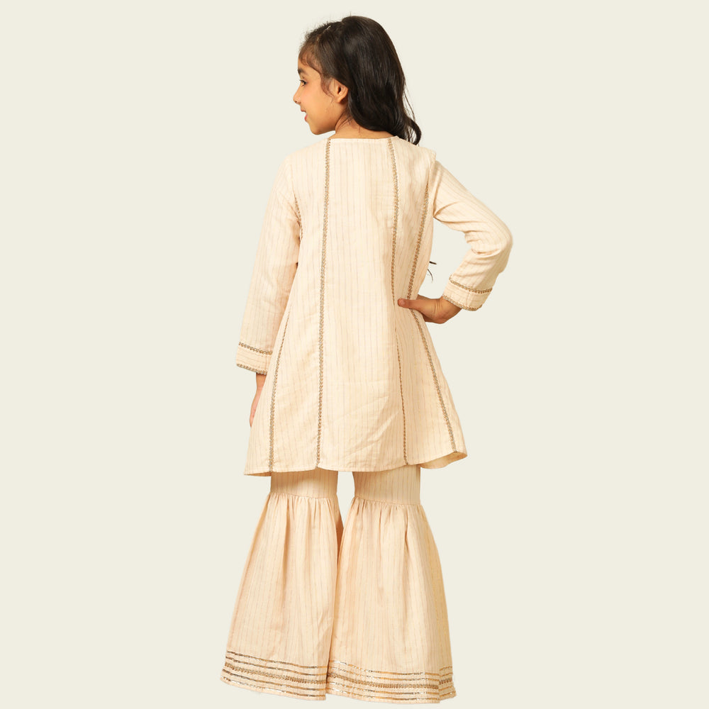 
                  
                    Elegant in its simplicity, the Rajni Sharara Set is a refined ensemble for special occasions. Crafted in a soft ivory-peach hue with subtle&nbsp;pinstripes, this set features a straight-cut kurta with delicate gold threadwork detailing on the yoke and sleeves. 
                  
                