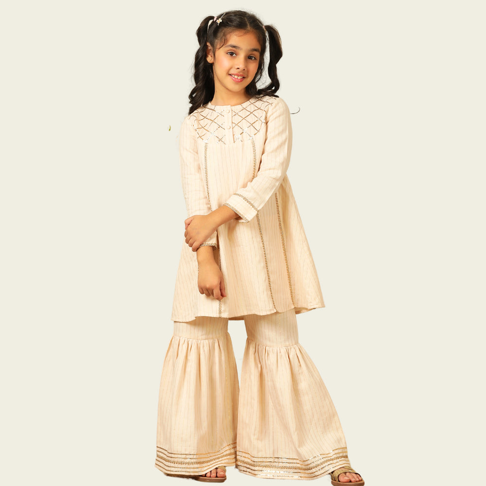 
                  
                    Elegant in its simplicity, the Rajni Sharara Set is a refined ensemble for special occasions. Crafted in a soft ivory-peach hue with subtle&nbsp;pinstripes, this set features a straight-cut kurta with delicate gold threadwork detailing on the yoke and sleeves. 
                  
                