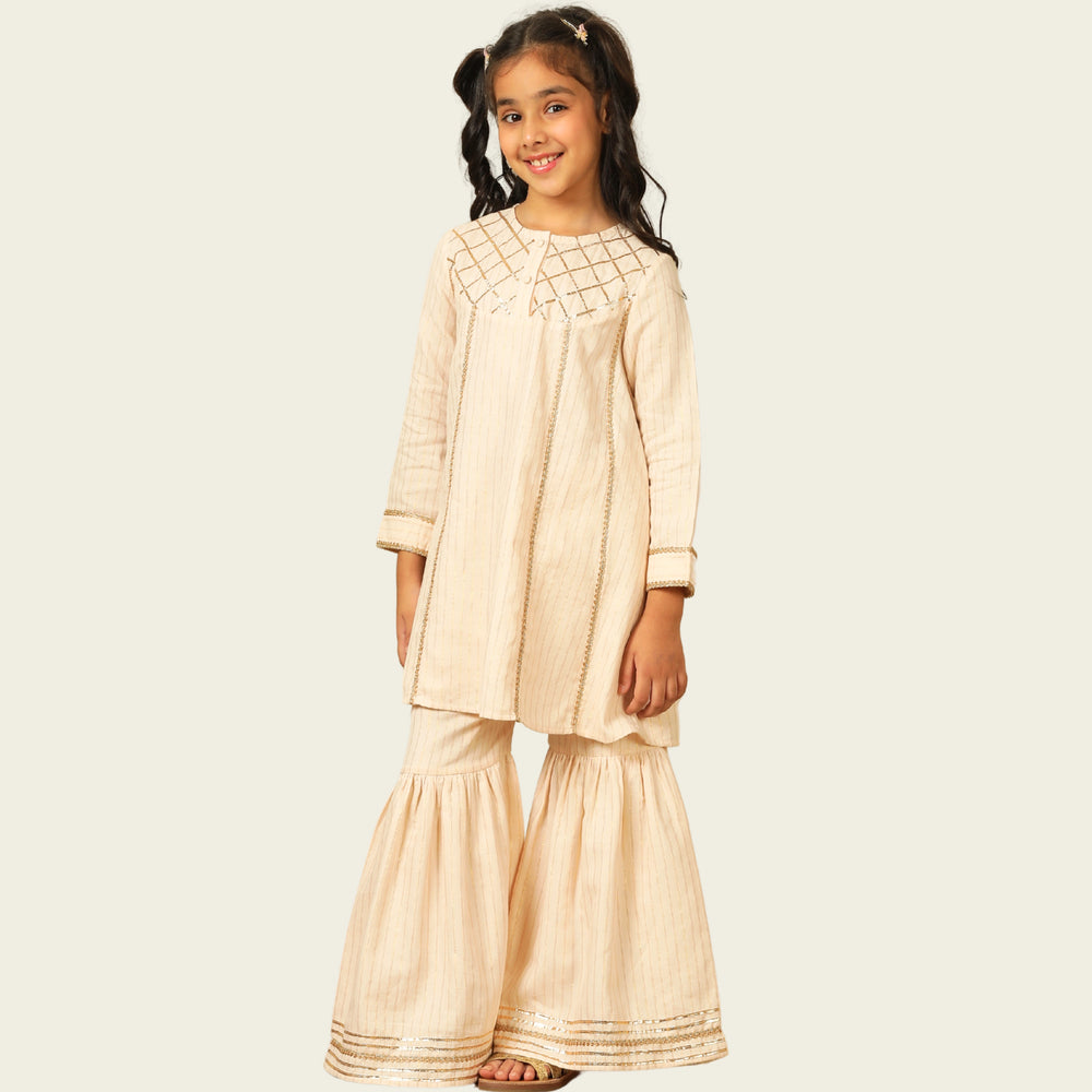
                  
                    Elegant in its simplicity, the Rajni Sharara Set is a refined ensemble for special occasions. Crafted in a soft ivory-peach hue with subtle&nbsp;pinstripes, this set features a straight-cut kurta with delicate gold threadwork detailing on the yoke and sleeves. 
                  
                