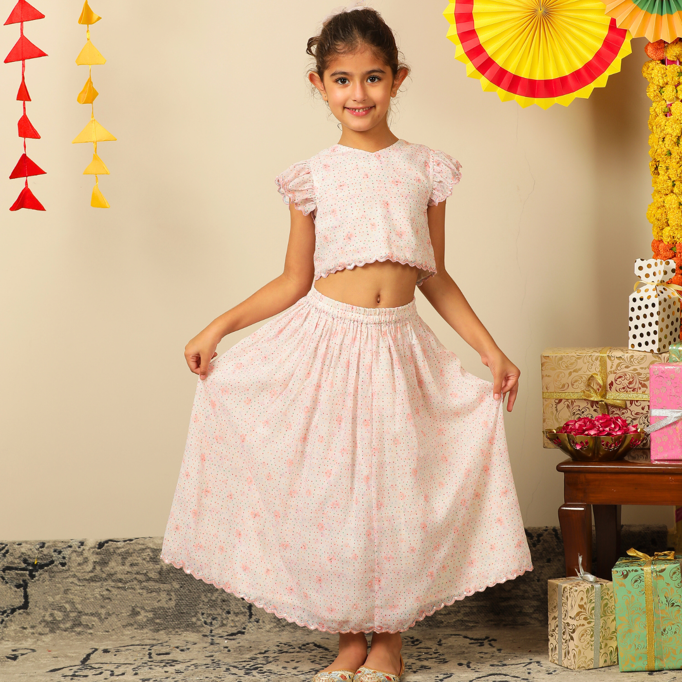 The Aabha Lehenga Dress Set is a sweet and sparkly outfit made for magical moments. Crafted in a soft pastel pink base, this dress is adorned with delicate floral prints and shimmering polka dots all over. 