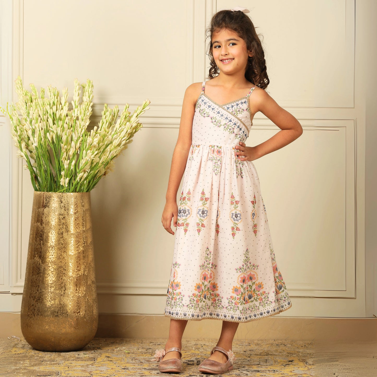  a graceful Indo-Western dress that blends tradition with whimsy. Crafted in soft, flowy Chanderi fabric, this dress features delicate floral prints, a flattering asymmetrical neckline, and dainty bead detailing along the straps and hem. 