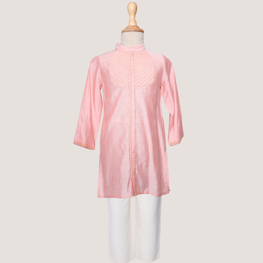 A boys' Kurta and Pyjama set with the kurta in pink and pyjama in white, displaying subtle zari embroidery on the yoke, placket, and cuffs.