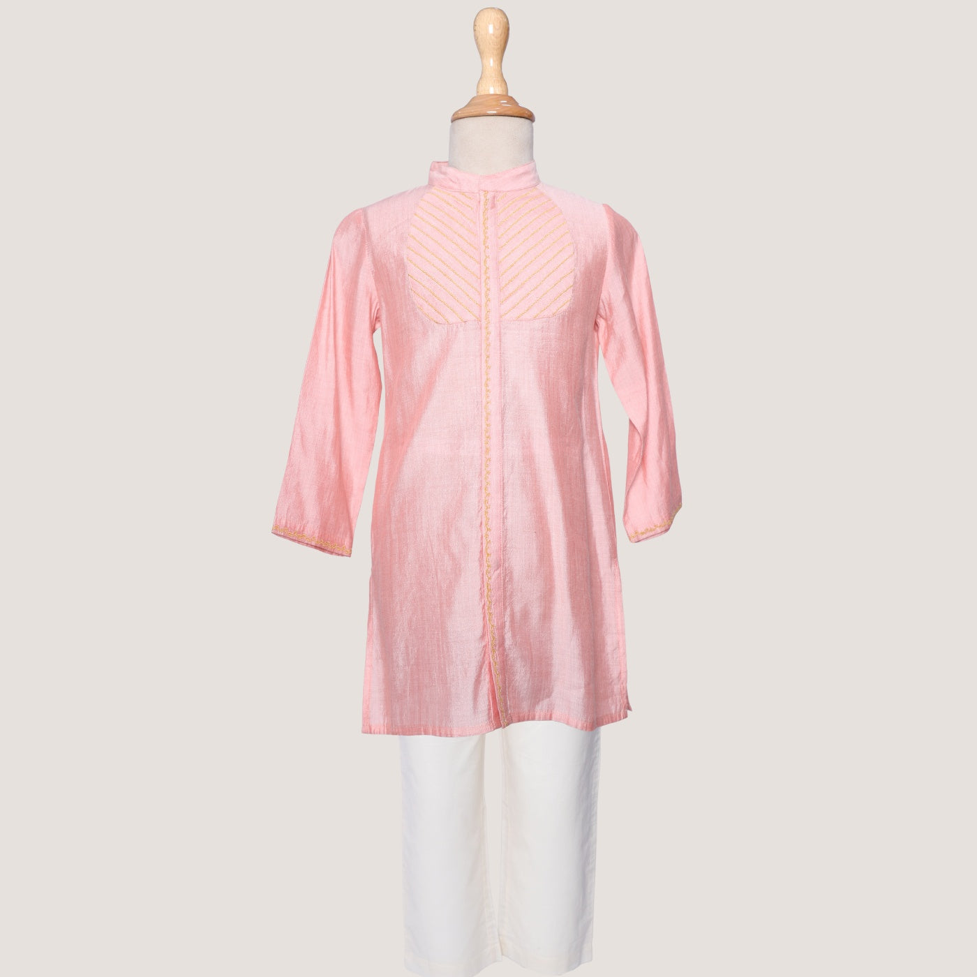 A boys' Kurta and Pyjama set with the kurta in pink and pyjama in white, displaying subtle zari embroidery on the yoke, placket, and cuffs.