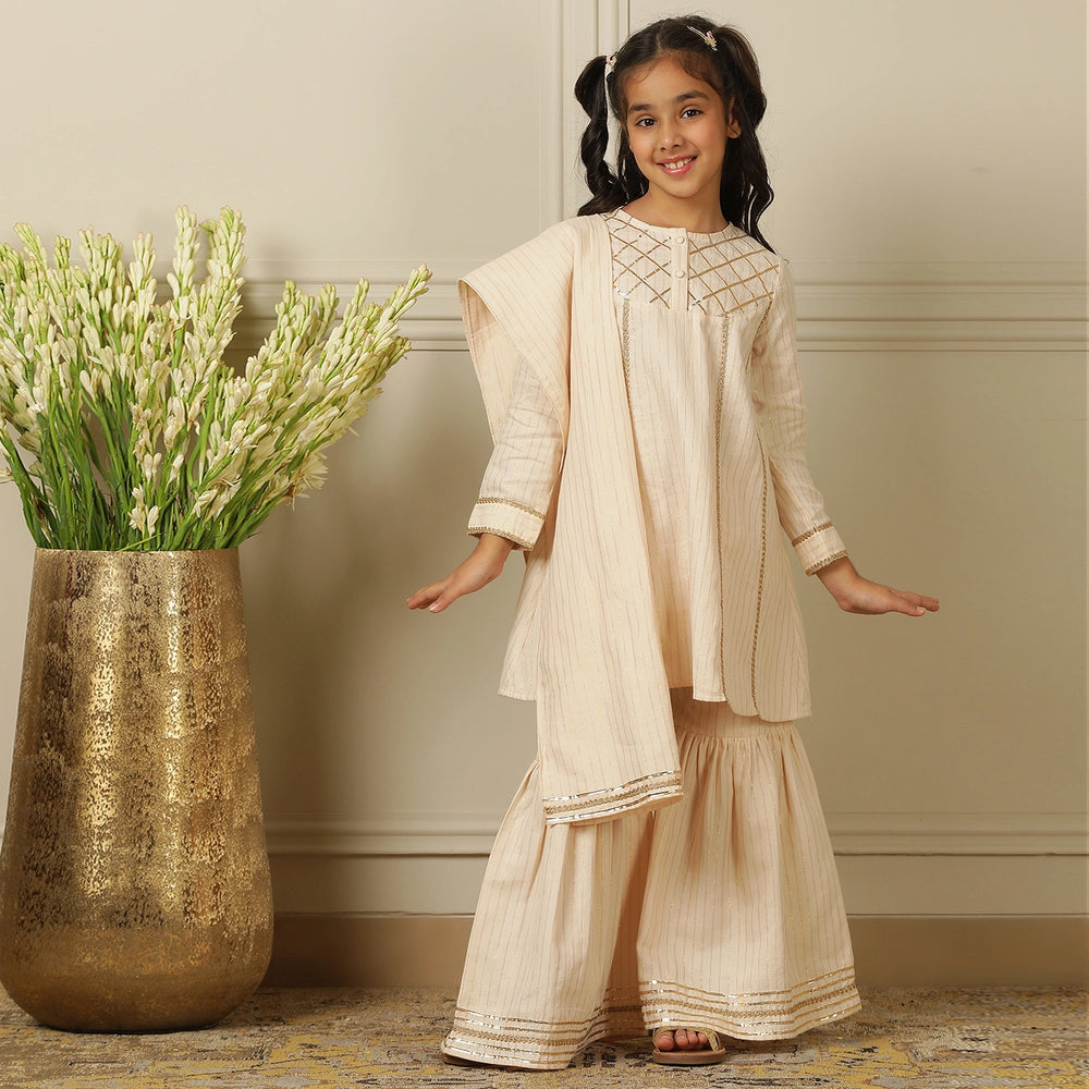 
                  
                    Elegant in its simplicity, the Rajni Sharara Set is a refined ensemble for special occasions. Crafted in a soft ivory-peach hue with subtle&nbsp;pinstripes, this set features a straight-cut kurta with delicate gold threadwork detailing on the yoke and sleeves. 
                  
                