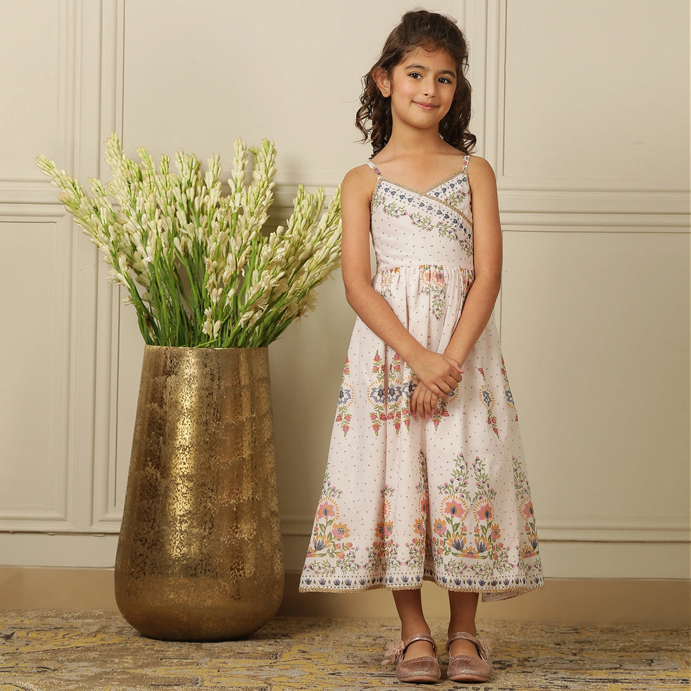
                  
                     a graceful Indo-Western dress that blends tradition with whimsy. Crafted in soft, flowy Chanderi fabric, this dress features delicate floral prints, a flattering asymmetrical neckline, and dainty bead detailing along the straps and hem. 
                  
                